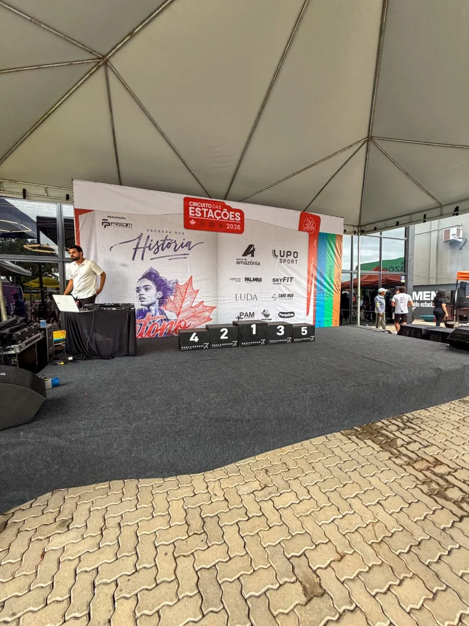 Palco de premiação com pódio e backdrop sob tenda no Circuito das Estações em Palmas-TO